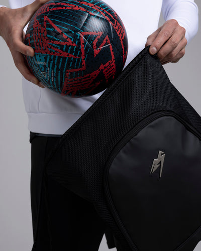 A person placing a football in the Kaliaaer Pro Gymsack in black.