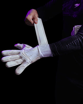 A person fastening the wrists of Kaliaaer white goalkeeper gloves