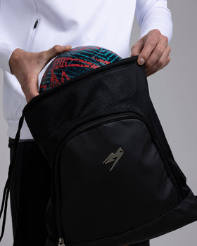 A person placing a football in the Kaliaaer Pro Gym sack.