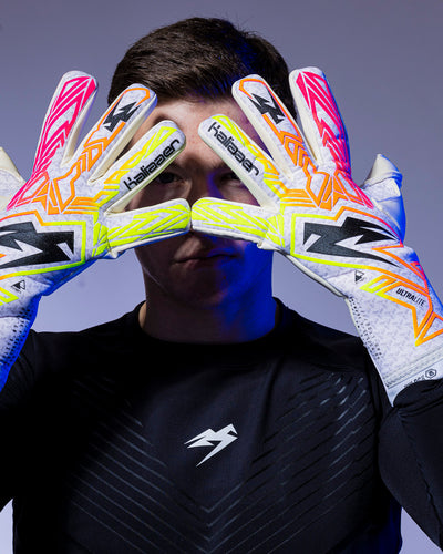 man holds up pink and neon kaliaaer goalkeeper gloves