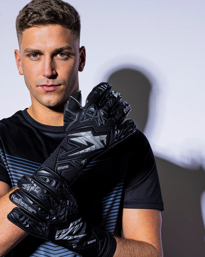 Person wearing black and silver kaliaaer strapless goalkeeper gloves