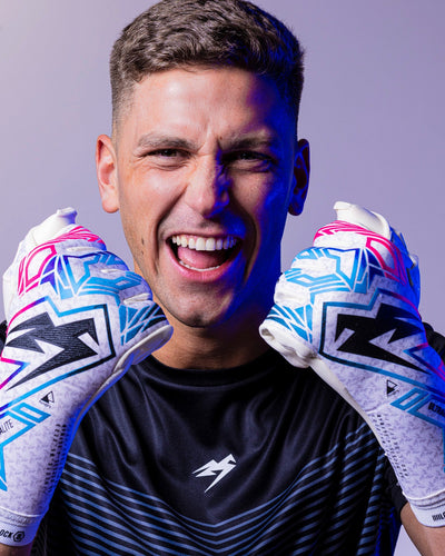 Boy holding junior strapless goalkeeper gloves in pink and blue colours. 