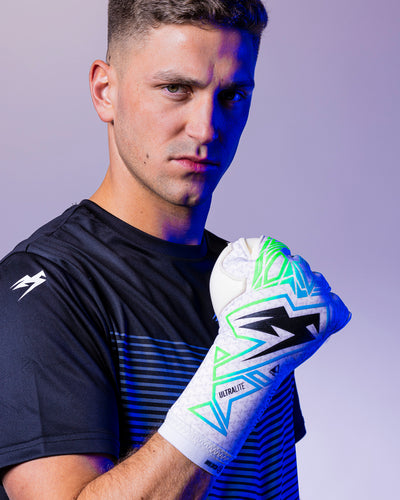 man with clenched fist in green and blue strapless goalkeeper gloves