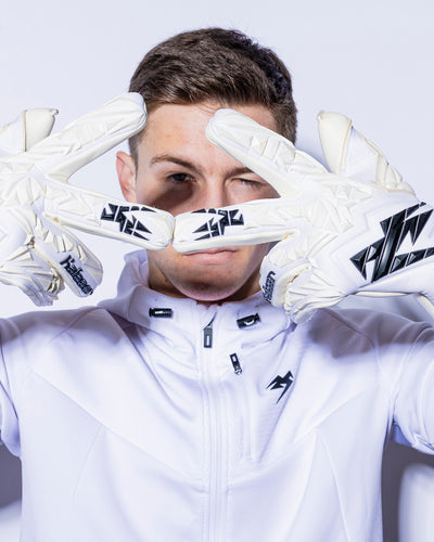 person wearing kaliaaer white strapless goalkeeper gloves has hands at his face