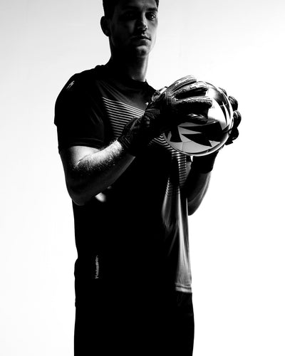 Person holding ball wearing black junior goalkeeper gloves