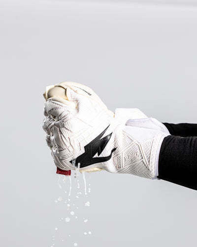 A person squeezing water out of Kaliaaer goalkeeper gloves.